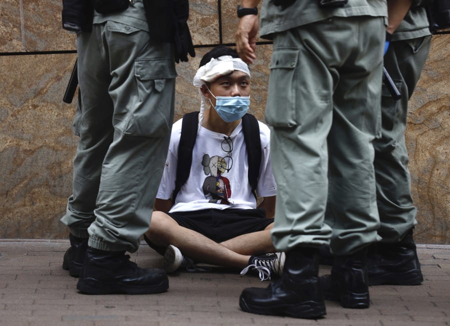 Riot police guard a protester as a second reading of a controversial national anthem law takes place in Central district, Hong Kong, Wednesday, May 27, 2020. Hong Kong police massed outside the legislature complex Wednesday, ahead of debate on a bill that would criminalize abuse of the Chinese national anthem in the semi-autonomous city.