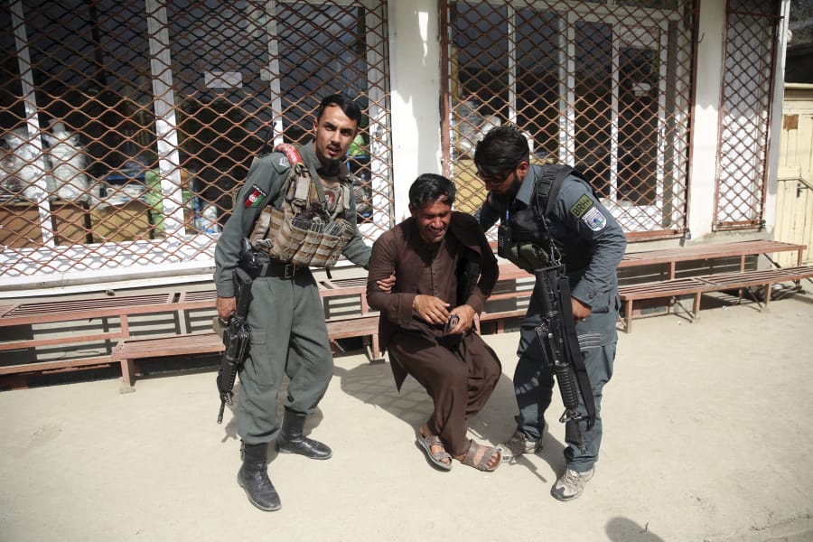 Afghan policemen comfort a man after an attack on a maternity hospital, in Kabul, Afghanistan, Tuesday, May 12, 2020.