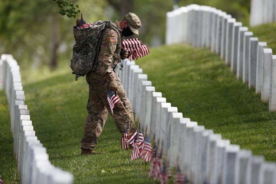 A member of the 3rd U.S. Infantry Regiment also known as The Old Guard, wears a face mask as he places flags in front of each headstone for &quot;Flags-In&quot; at Arlington National Cemetery in Arlington, Va., Thursday, May 21, 2020, to honor the Nation&#039;s fallen military heroes ahead of Memorial Day.