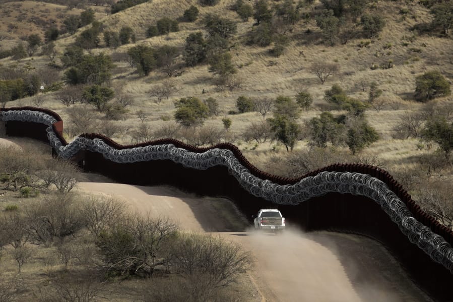 FILE - This March 2, 2019, file photo, shows a Customs and Border Control agent patrolling on the US side of a razor-wire-covered border wall along the Mexico east of Nogales, Ariz. A North Dakota construction company favored by President Donald Trump has received the largest contract to build a wall along the U.S.-Mexico border. The Army Corp of Engineers also said there was no set date to start or complete construction, which will take place near Nogales, Arizona and Sasabe, Arizona.