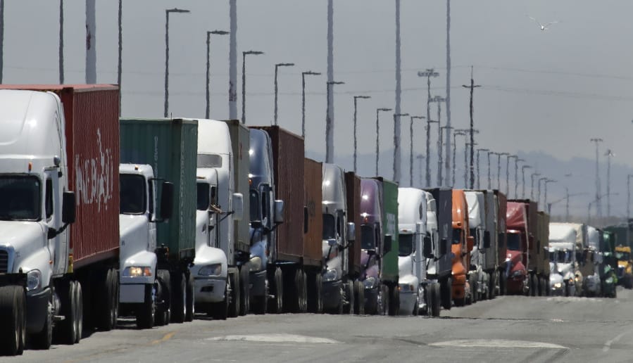 FILE - In this July 22, 2019 photo, trucks hauling shipping containers wait to unload at the Port of Oakland in Oakland, Calif.  The Commerce Department issues its second estimate of how the U.S.