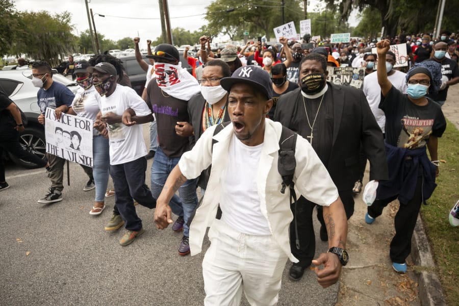 Malik Muhammad, center, joins a group of people marching from the Glynn County Courthouse in downtown to a police station after a rally to protest the shooting of Ahmaud Arbery, Saturday, May 16, 2020, in Brunswick, Ga. (AP Photo/Stephen B.
