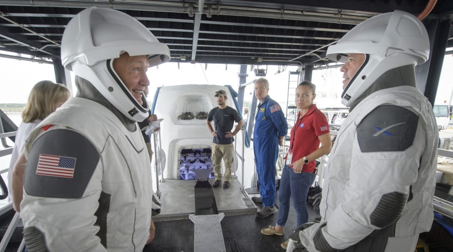 FILE - In this Aug. 13, 2019 file photo, NASA astronauts Doug Hurley, left, and Bob Behnken work with teams from NASA and SpaceX to rehearse crew extraction from SpaceX&#039;s Crew Dragon, which will be used to carry humans to the International Space Station, at the Trident Basin in Cape Canaveral, Fla. For the first time in nearly a decade, astronauts are about to blast into orbit aboard an American rocket from American soil. And for the first time in the history of human spaceflight, a private company -- SpaceX -- is providing the ride.