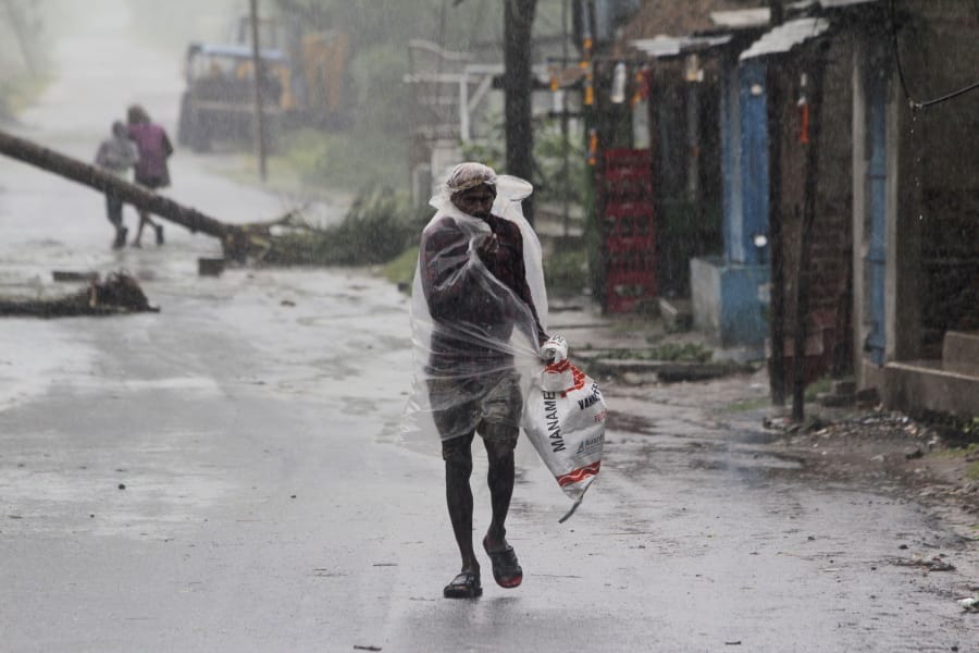 A man covers himself with a plastic sheet and walks in the rain ahead of Cyclone Amphan landfall, at Bhadrak district, in the eastern Indian state of Orissa, Wednesday, May 20, 2020. A strong cyclone blew heavy rains and strong winds into coastal India and Bangladesh on Wednesday after more than 2.6 million people were moved to shelters in a frantic evacuation made more challenging by coronavirus.
