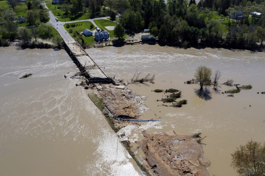 In this Wednesday, May 20, 2020, photo, people survey the flood damage to the Curtis Road Bridge in Edenville, Mich., over the Tittabawassee River. The bridge sits just south of Wixom Lake where the dams failed.