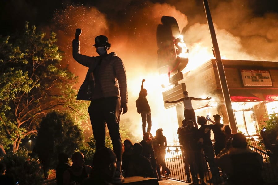 Protestors demonstrate outside of a burning fast food restaurant, Friday, May 29, 2020, in Minneapolis. Protests over the death of George Floyd, a black man who died in police custody Monday, broke out in Minneapolis for a third straight night.