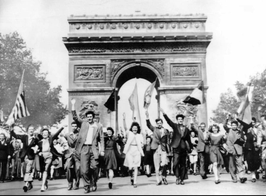 FILE - In this May 8, 1945 file photo Parisians march through the Arc de Triomphe jubilantly waving flags of the Allied Nations as they celebrate the end of World War II in Europe. Nazi commanders signed their surrender to Allied forces in a French schoolhouse 75 years ago this week, ending World War II in Europe and the Holocaust.