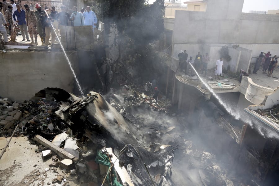 Fire brigade staff try to put out fire caused by plane crash in Karachi, Pakistan, Friday, May 22, 2020. An aviation official says a passenger plane belonging to state-run Pakistan International Airlines carrying more than 100 passengers and crew has crashed near the southern port city of Karachi. There were no immediate reports on the number of casualties.