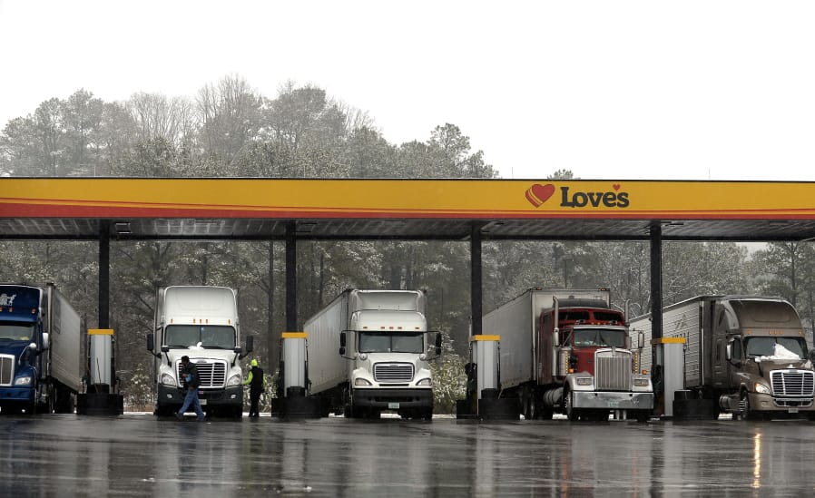 FILE - In this Feb. 11, 2014, file photo, truck drivers stop at a gas station in Emerson, Ga., north of metro Atlanta, to fill up their tractor trailer rigs. The Trump administration eased rules Thursday, May 14, 2020 that limit working hours for truck drivers, and the changes brought immediate protests from labor and safety groups. The Federal Motor Carrier Safety Administration extended the maximum working day for short-haul drivers from 12 hours to 14 hours and applied the longer hours to more drivers by expanding the geographic definition of short-haul driving.
