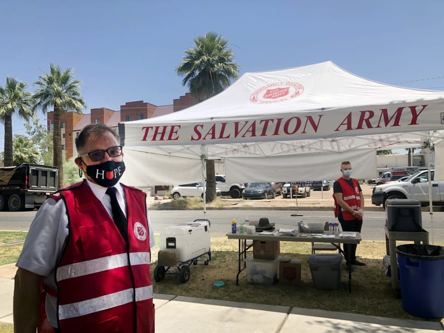 Salvation Army Maj. David Yardley, left, stands outside the Salvation Army Phoenix downtown headquarters where a heat relief station was set up on Thursday, May 28, 2020, in Phoenix, Ariz. A heat relief station offering cold water and a cool place inside to rest out of the brutal sun will be open every day through Sunday while an excessive heat warning is in effect.