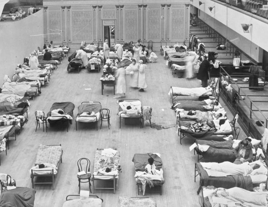 FILE - In this 1918 file photo made available by the Library of Congress, volunteer nurses from the American Red Cross tend to influenza patients in the Oakland Municipal Auditorium, used as a temporary hospital. Science has ticked off some major accomplishments over the last century. The world learned about viruses, cured various diseases, made effective vaccines, developed instant communications and created elaborate public-health networks. Yet in many ways, 2020 is looking like 1918, the year the great influenza pandemic raged. (Edward A.