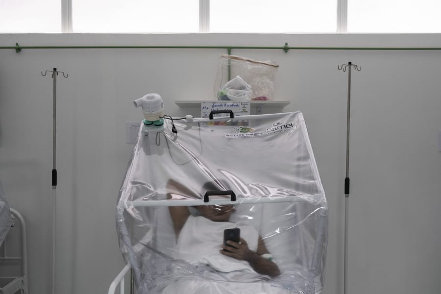 A COVID-19 patient uses his phone as he is treated inside a non-invasive ventilation system named the &quot;Vanessa Capsule&quot; at the municipal field hospital Gilberto Novaes in Manaus, Brazil, Monday, May 18, 2020. The field hospital set up inside a school currently has nearly 150 beds and is operating near its limit as it treats patients both from the capital and from rural areas of Amazon state.