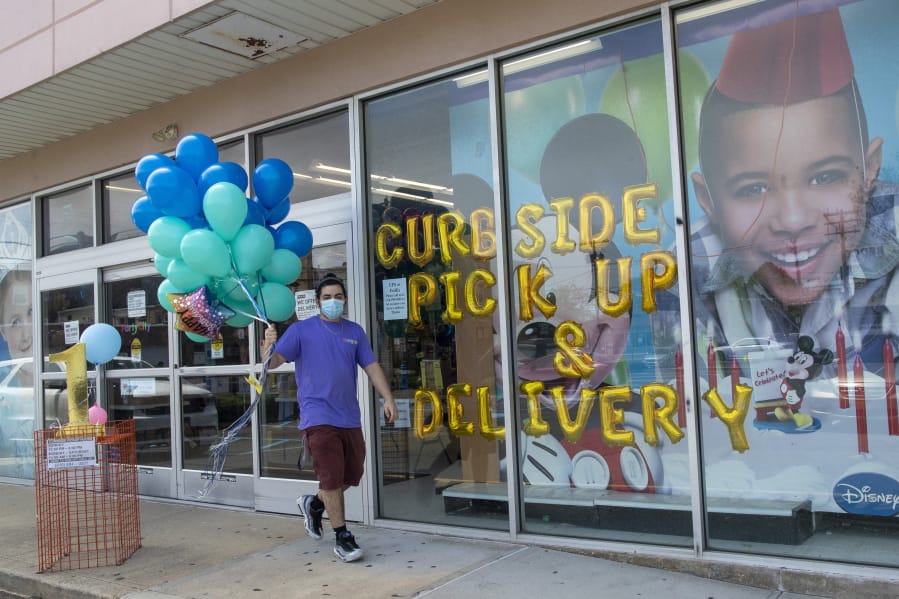 A Party City employee delivers balloons to a customer curbside, Wednesday, May 27, 2020, in Oceanside, N.Y. Long Island has become the latest region of New York to begin easing restrictions put in place to curb the spread of the coronavirus as it enters the first phase of the state&#039;s four-step reopening process.