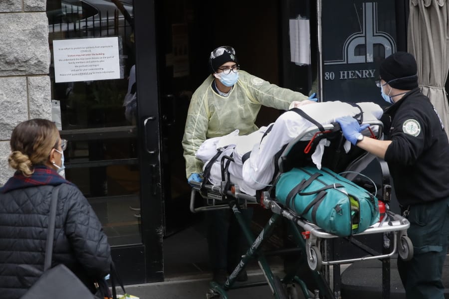 FILE- In this April 17, 2020, file photo, a patient is wheeled into Cobble Hill Health Center by emergency medical workers in the Brooklyn borough of New York. On Thursday, April 23, 2020, New York Gov. Andrew Cuomo said that nursing homes in New York must immediately report how they have complied with regulations for resident care during the coronavirus, and non-compliant facilities could face hefty fines or lose their licenses.