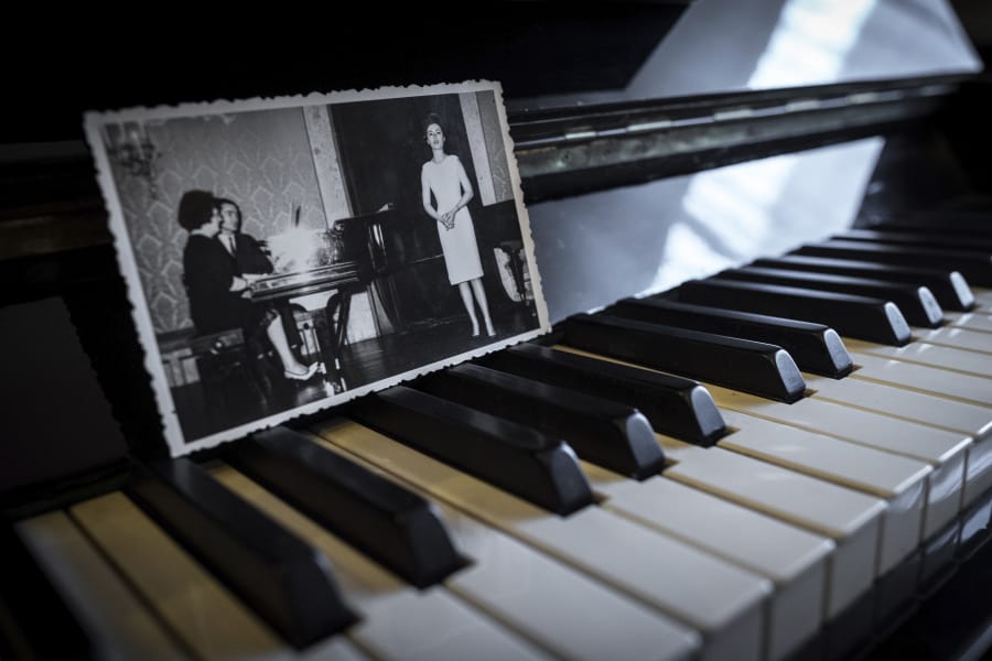 In this picture taken, April 26, 2020, a family album photograph showing Hannelore Fischer Cruz singing is placed on her piano at the house where she used to live in Braga, northern Portugal. Born amid the ruins of wartime Vienna, Hannelore Fischer was sent as a small child to Portugal where her flamboyant manner and outstanding soprano voice would later help her build a life far from her place of birth. She died of COVID-19 on March 25, 2020, after four days on a ventilator at Braga&#039;s hospital.