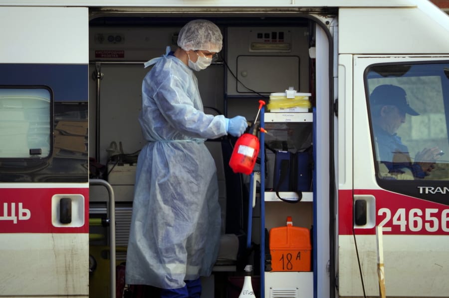 A medical worker wearing protective equipment sprays disinfectant at his ambulance after delivering a patient suspected of being infected with the coronavirus to the Pokrovskaya hospital in St.Petersburg, Russia, Monday, May 4, 2020.