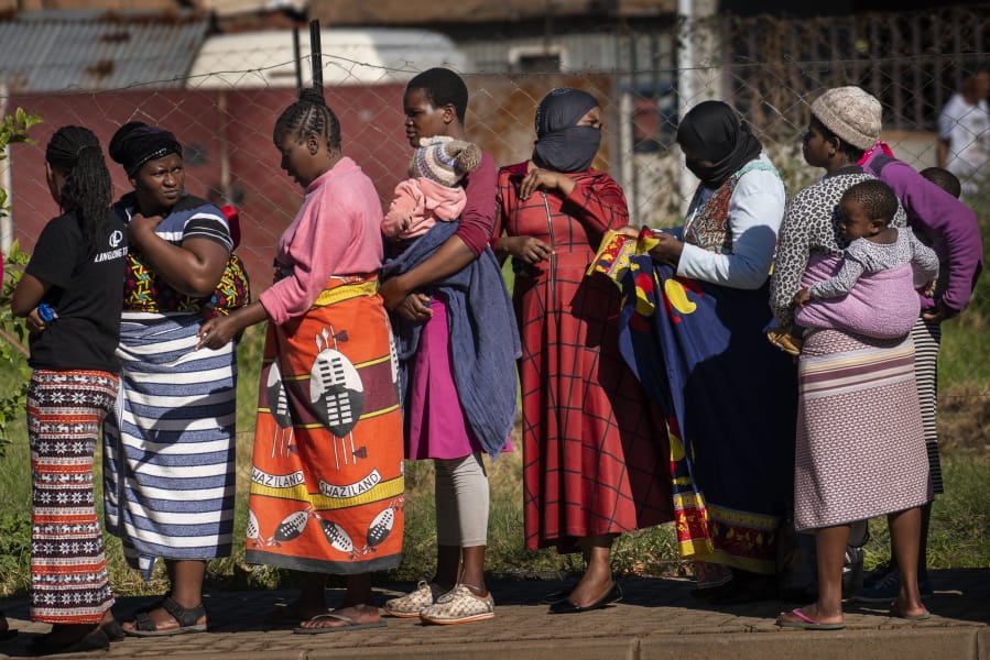 FILE- In this file photo taken Thursday, April 30, 2020, Women carrying their children lineup to receive vegetables from the Jan Hofmeyer community services in the Vrededorp neighborhood of Johannesburg. South Africa is struggling to balance its fight against the coronavirus with its dire need to resume economic activity. The country with the Africa&#039;s most developed economy also has its highest number of infections -- more than 19,000.