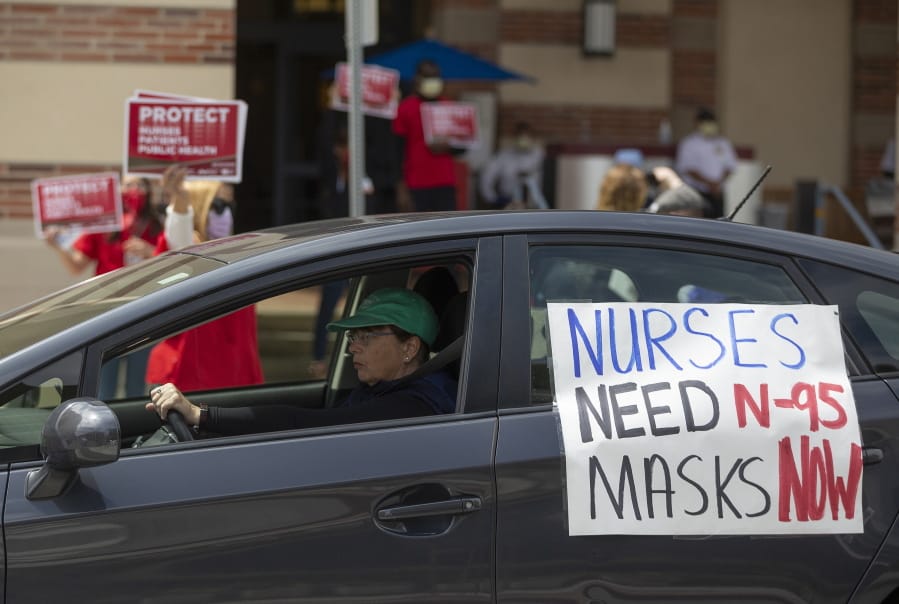 FILE - In this April 13, 2020, file photo, a car passes nurses protesting the lack of N95 respirators and other Personal Protective Equipment outside the UCLA Medical Center, Santa Monica amid the coronavirus pandemic in Santa Monica, Calif. An Associated Press review of more than 20 states found that before the coronavirus outbreak many had at least a modest supply of N95 masks, gowns, gloves and other medical equipment. But those were often well past their expiration dates -- left over from the H1N1 influenza outbreak a decade ago.