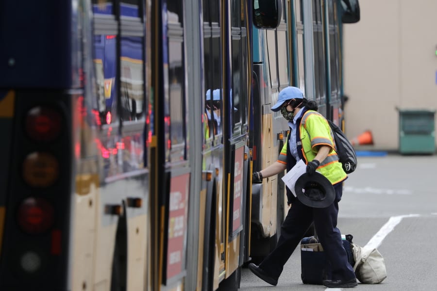 A King County Metro bus driver wipes down a handrail before stepping onto a bus Monday, May 11, 2020, in Seattle. The coronavirus pandemic has plunged Puget Sound-area transit agencies into crisis-planning mode, as ridership and revenue has plunged and predictions that people will not be returning to buses and trains in large numbers anytime soon. The Seattle Times reports that beyond the immediate health crisis, the pandemic threatens to undo years of transit growth and plunge local transit systems into a financial setback worse than the Great Recession in the late 2000s.