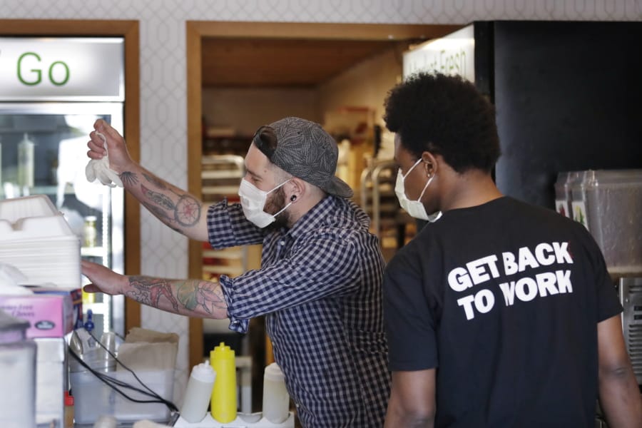 Falafel shop workers Bryant Movern, left, and Javohn Ferguson work to pack customer&#039;s take-out orders in a restaurant otherwise closed because of the coronavirus outbreak Tuesday, May 19, 2020, in Seattle. Washington state Gov. Jay Inslee on Tuesday announced $10 million in grants to small businesses in industries particularly hard-hit by the COVID-19 outbreak. They include restaurants, hair salons, fitness studios and theaters.