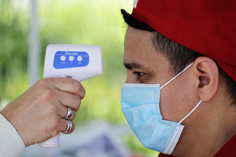 Edwin Hernandez has his temperature checked as part of a screening for coronavirus symptoms at a portable testing site for maritime workers at Fisherman&#039;s Terminal Wednesday, May 27, 2020, in Seattle.