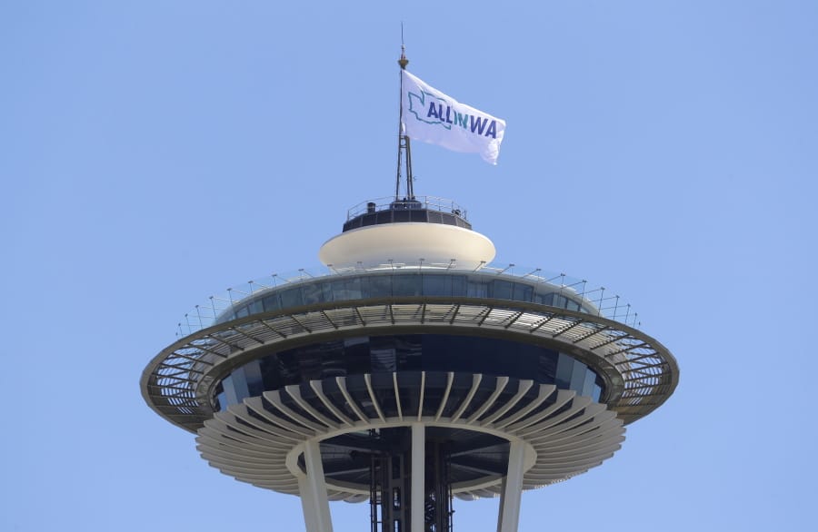 A flag promoting the All In WA relief effort flies Wednesday atop the Space Needle in Seattle. Southwest Washington is participating in the statewide campaign aimed at helping people impacted by the COVID-19 pandemic. (Ted S.