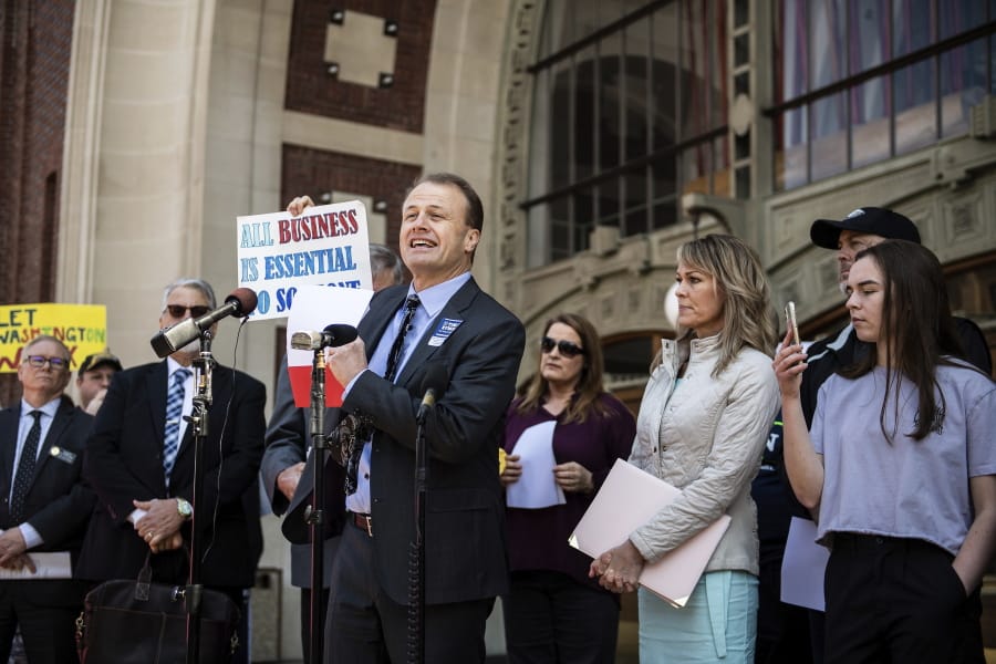 Then-Gubernatorial candidate Tim Eyman, center, speaks during a news conference outside of the United States District Courthouse in Union Station in Tacoma, Wash., Friday, May 1, 2020. Eyman and others sued Gov. Jay Inslee, Friday in U.S. District Court in Tacoma, alleging his orders during the pandemic to help stop the spread of COVID-19 have violated their constitutional rights.