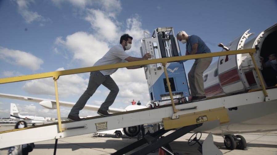 Elliot and Arthur Kreitenberg push the GermFalcon on a plane to disinfect the cabin.
