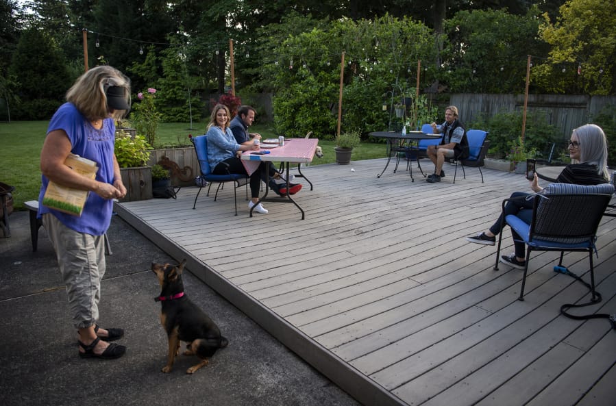 Laura Kok feeds her daughter&#039;s dog Zero as the family enjoys dinner together outside their home in Vancouver earlier this month. Since the pandemic stay-home orders were issued in March, the family has been coming together in Laura and Jeroen Kok&#039;s backyard for a socially distanced dinner at least once a week. Their youngest daughter, who lives out of town, joins via an online video call.