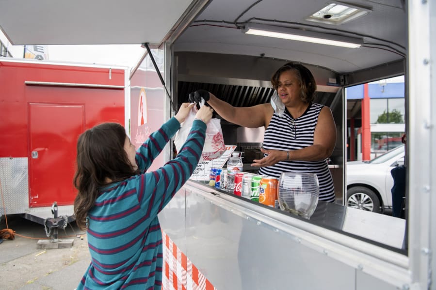 Natalie Oliver of Vancouver, left, picks up an order from Dorothy Golson at Golson&#039;s food cart, Southern Girl Delights. Golson said she opened the food cart in Hazel Dell a year ago, with a menu inspired by her upbringing in Alabama. &quot;I always followed my mom around in the kitchen,&quot; she said.