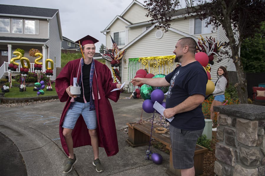 Prairie High School graduate David Hatcher, 18, left, celebrates his accomplishments with Victor Paskar on Friday evening during a neighborhood graduation ceremony for the class of 2020 in Orchards. The students marked the occasion with a cul-de-sac graduation with nearby families as COVID-19 concerns forced the cancellation of their scheduled in-person ceremonies.