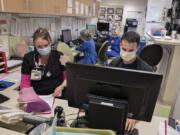 Registered nurses Wendy Stephens, left, and Joe Fistolera join colleagues in wearing masks while working in the short stay unit at Legacy Salmon Creek Medical Center in Vancouver.