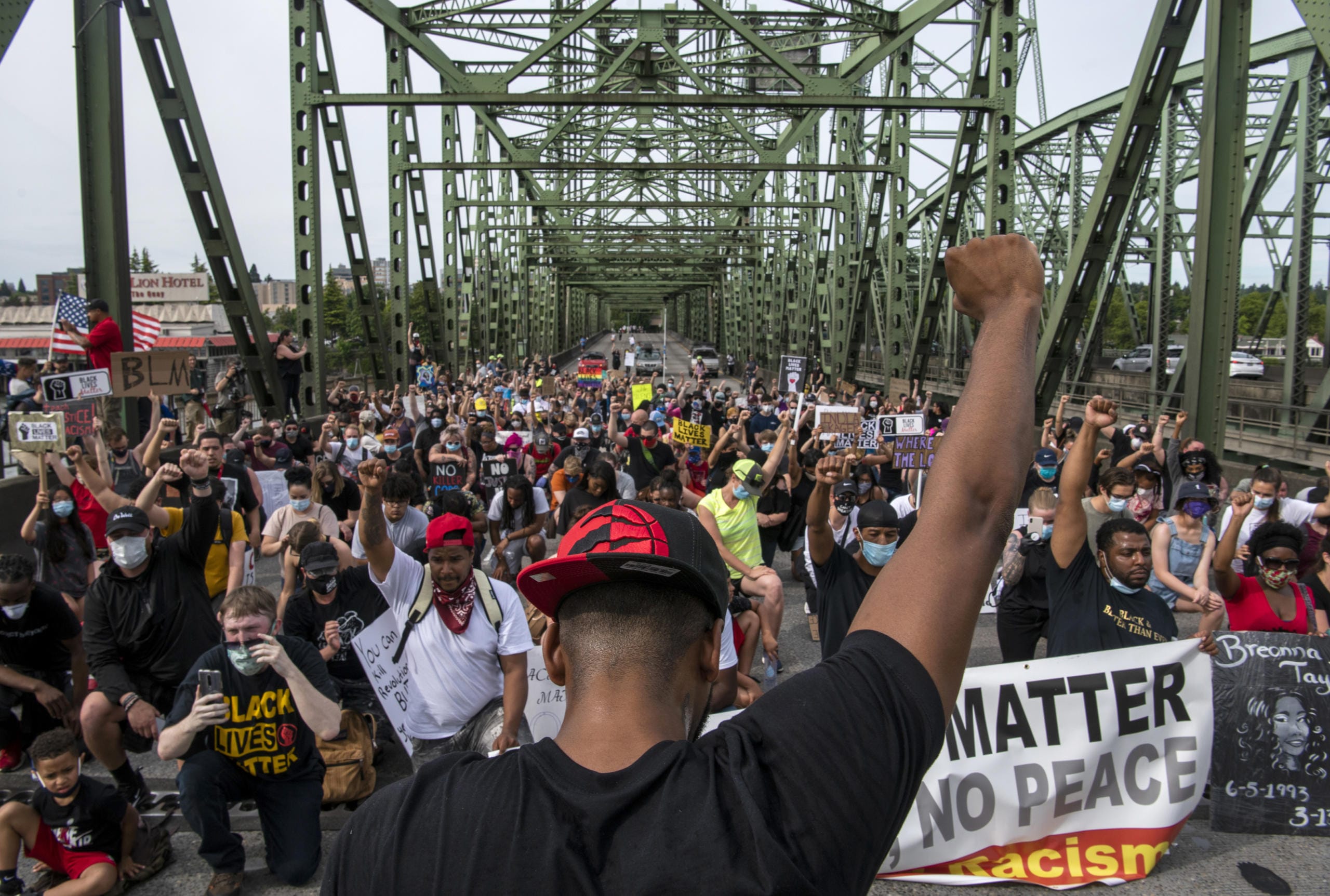 Hundreds of demonstrators take a knee for one minute to honor Black lives lost to police violence on the Interstate 5 bridge Friday afternoon, June 19, 2020.