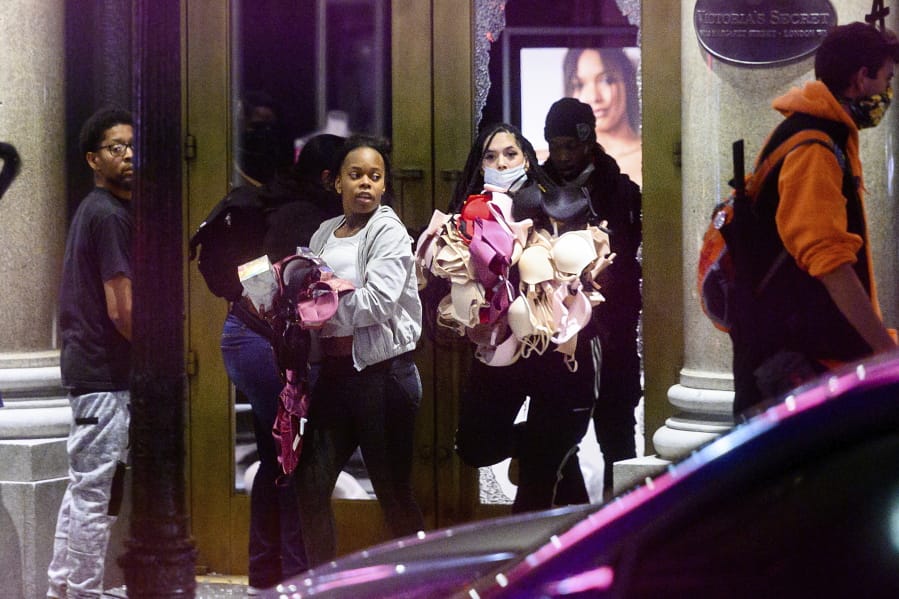 FILE - In this May 30, 2020, file photo, women carry merchandise from a Union Square Victoria&#039;s Secret store in San Francisco. Police say many of the smash-and-grab thefts have been carried out by caravans of well-coordinated criminals that have coincided with or followed protests over the death of George Floyd, who was killed by a Minneapolis police officer who pressed his knee into Floyd&#039;s neck.