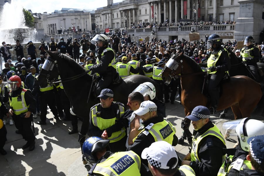 A wounded member of a far-right group is escorted by British police officers in riot gear, during scuffles as police tries to contain a protest at Trafalgar Square in central London, Saturday, June 13, 2020. British police have imposed strict restrictions on groups protesting in London Saturday in a bid to avoid violent clashes between protesters from the Black Lives Matter movement, as well as far-right groups that gathered to counter-protest.