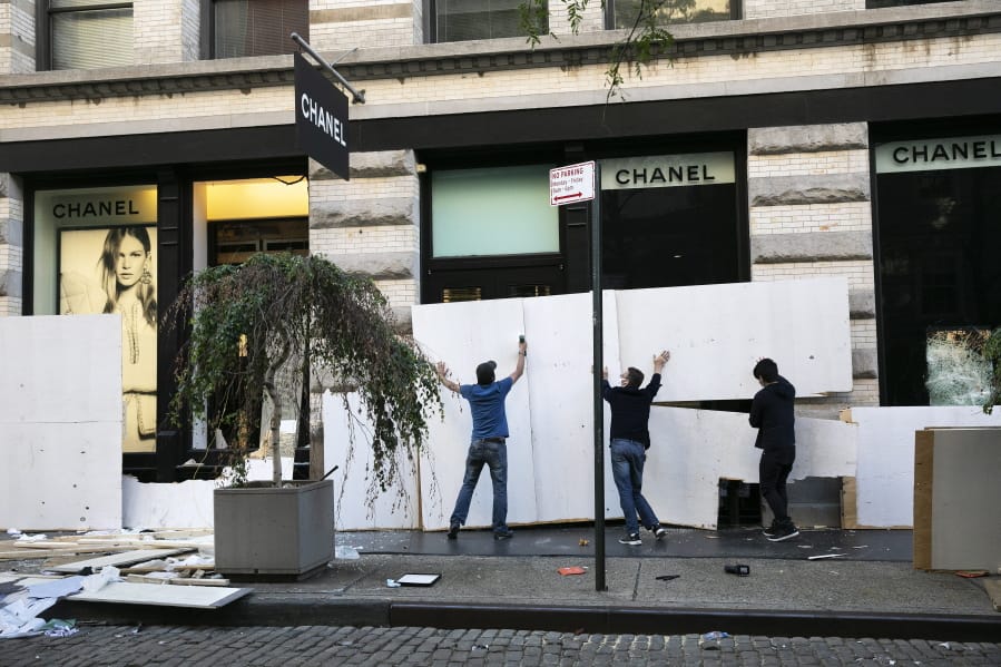 Workers board up the windows of a Chanel store Monday, June 1, 2020, following protests in the SoHo neighborhood of New York. Protests were held throughout the country over the death of George Floyd, a black man who died after being restrained by Minneapolis police officers on May 25.