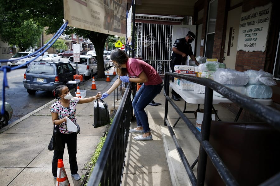 In this June 11, 2020, photo Lourdes Sherby, center, with Guadalupe Family Services, hands diapers to Louisa Peralta in Camden, N.J. &quot;I think we&#039;re received a lot better than we used to be,&quot; said Sgt. Dekel Levy, 41, as he helped hand out diapers to a steady stream of young mothers Thursday afternoon at Guadalupe Family Service.