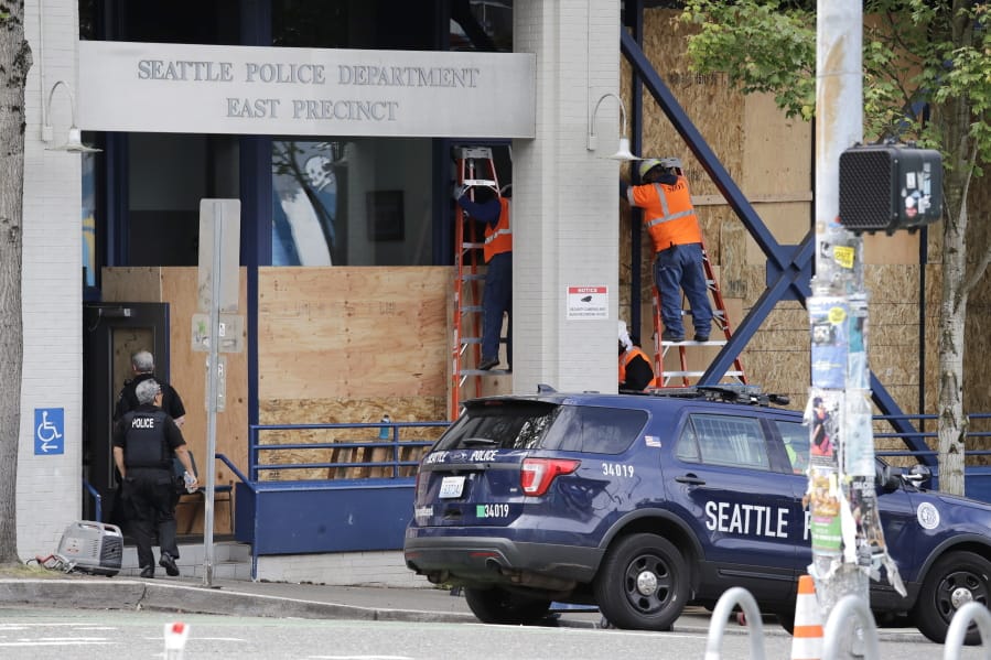 Workers put up plywood over the windows of a Seattle police precinct Monday, June 8, 2020, in Seattle, where protests continued the night before over the death of George Floyd, a black man who was in police custody in Minneapolis. Just days after Seattle&#039;s mayor and police chief promised a month-long moratorium on using a type of tear gas to disperse protesters, the department used it again.