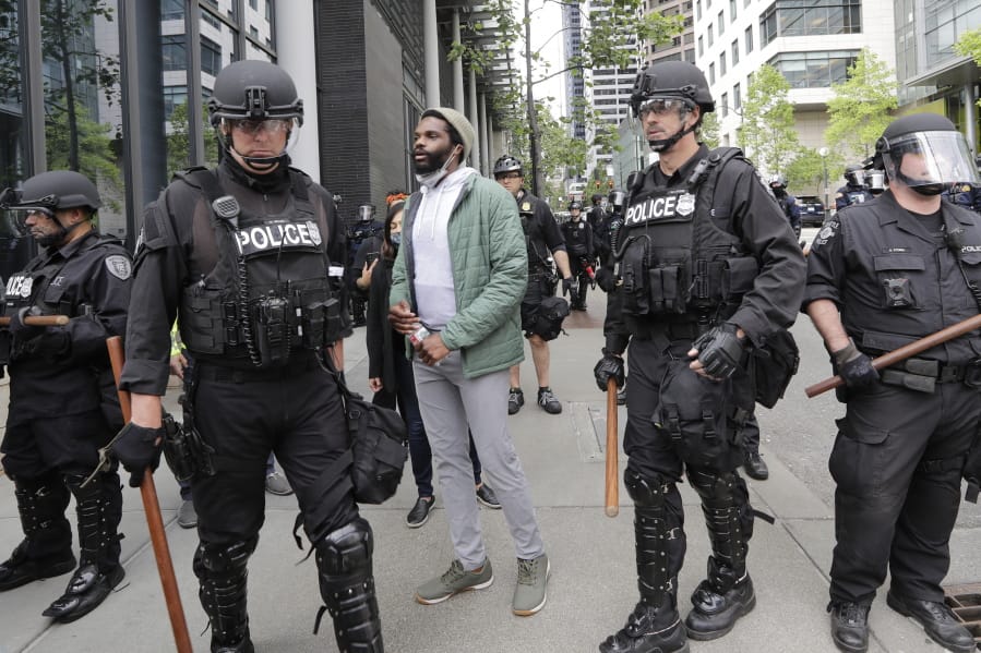 Activist David Lewis, center, walks past police officers as he heads in to Seattle City Hall to meet with the mayor Wednesday, June 3, 2020, in Seattle, following protests over the death of George Floyd, a black man who was in police custody in Minneapolis.