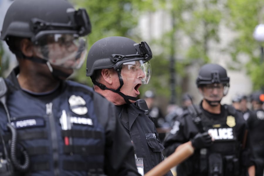 FILE - In this June 3, 2020, file photo, a Seattle police officer yells out orders at Seattle City Hall as protesters march toward them, in Seattle, following protests over the death of George Floyd, a black man who was in police custody in Minneapolis. The King County Labor Council, the largest labor group in the Seattle area, vote Wednesday night June 17 to expell the city&#039;Aos police union, saying the guild representing officers failed to address racism within its ranks.