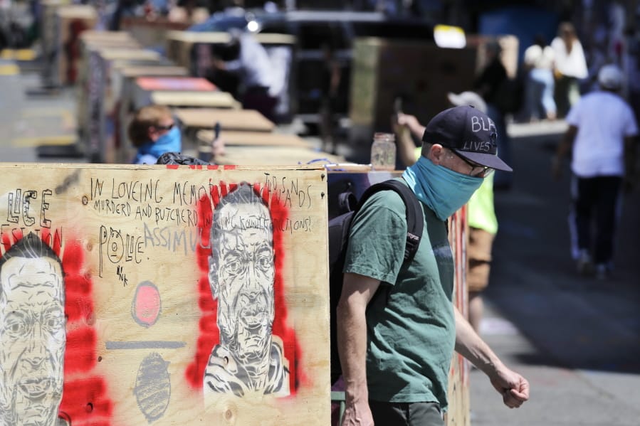 A man walks between barricades blocking a street adjacent to a closed police precinct Thursday, June 18, 2020, in Seattle, in what has been named the Capitol Hill Occupied Protest zone. Police pulled back from several blocks of the city&#039;s Capitol Hill neighborhood near the Police Department&#039;s East Precinct building earlier in the month after clashes with people protesting the death of George Floyd in Minneapolis.
