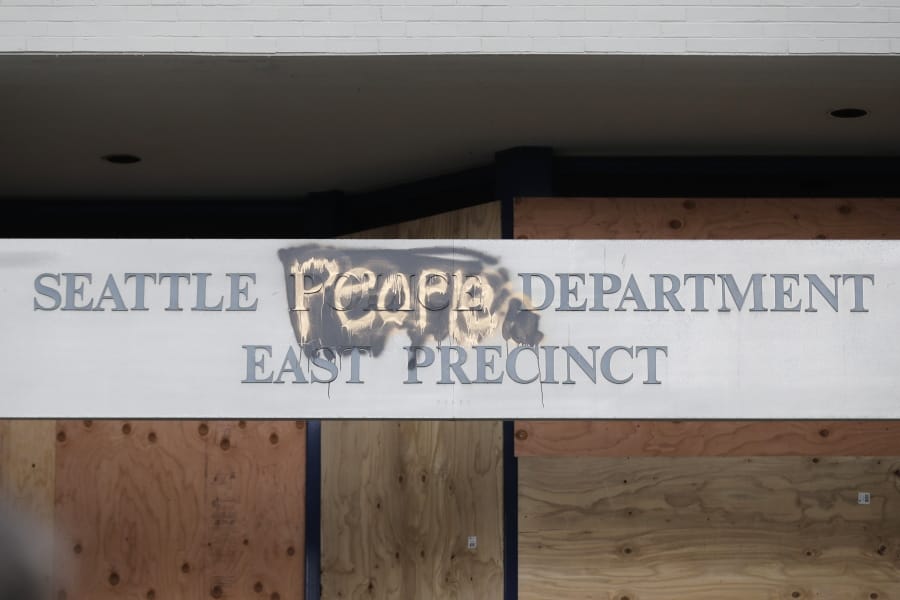 A modified sign for the Seattle Police Dept. East Precinct building, which has been boarded up and abandoned except for a few officers inside, is shown, Thursday, June 11, 2020, inside what is being called the &quot;Capitol Hill Autonomous Zone&quot; in Seattle. (AP Photo/Ted S.