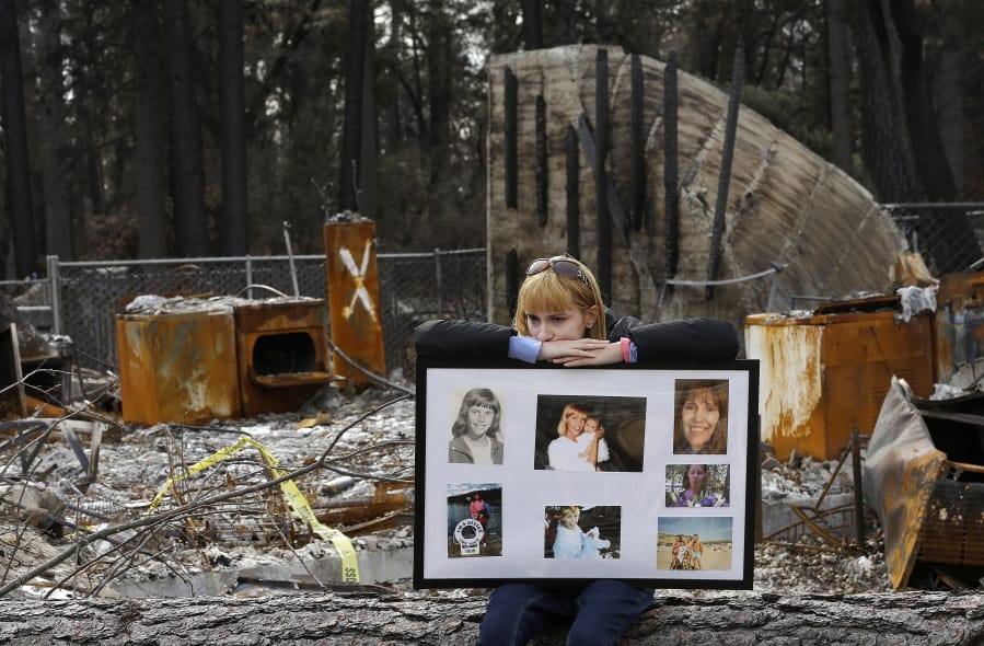 FILE - In this Feb. 7, 2019, file photo, Christina Taft, the daughter of Camp Fire victim Victoria Taft, displays a collage of photos of her mother, at the burned out ruins of the Paradise, Calif., home where she died in 2018. Pacific Gas &amp; Electric officials are to be expected to appear in court Tuesday, June 16, 2020, to plead guilty for the deadly wildfire that nearly wiped out the Northern California town of Paradise in 2018.