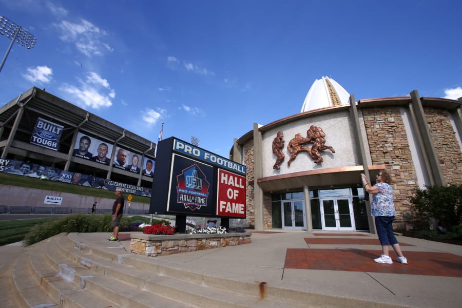 A visitor to the Pro Football Hall of Fame pauses to take a photo of the sign in front in Canton, Ohio. The NFL has canceled the 2020 Hall of Fame game that traditionally opens the preseason and is delaying the 2020 induction ceremonies because of the coronavirus pandemic. (AP Photo/Gene J.