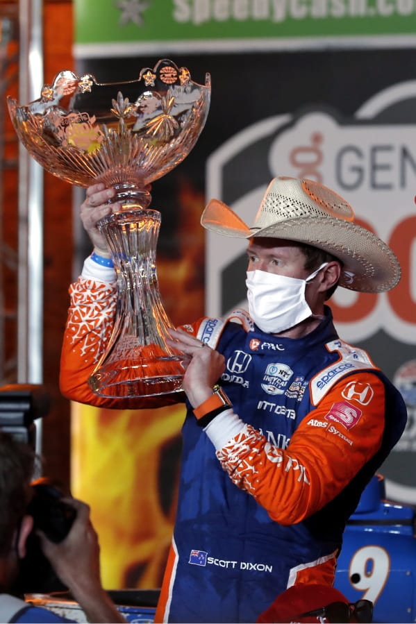 Scott Dixon holds up the winners trophy in Victory Lane after winning an IndyCar auto race at Texas Motor Speedway in Fort Worth, Texas, Saturday, June 6, 2020.