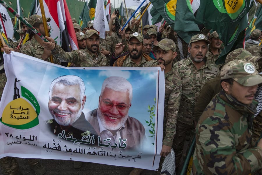 FILE - In this Saturday, Jan. 4, 2020 file photo, Iraqi militiamen march and chant anti U.S. slogans while carrying a picture of Soleimani, left and al-Muhandis, with Arabic that reads &quot;our martyr leaders,&quot; during the funeral of Iran&#039;s top general Qassem Soleimani and Abu Mahdi al-Muhandis, deputy commander of Iran-backed militias in Iraq known as the Popular Mobilization Forces, in Baghdad, Iraq. Iraqi militia leaders were expecting the usual bags of cash when the new head of Iran&#039;s expeditionary Quds Force , a successor Soleimani, paid his first visit. Instead, Esmail Ghani brought them silver rings, as tokens of gratitude. The episode, relayed by several officials, illustrates Iran&#039;s struggle to maintain influence abroad as it grapples with the economic fallout from crushing U.S. sanctions and the coronavirus.