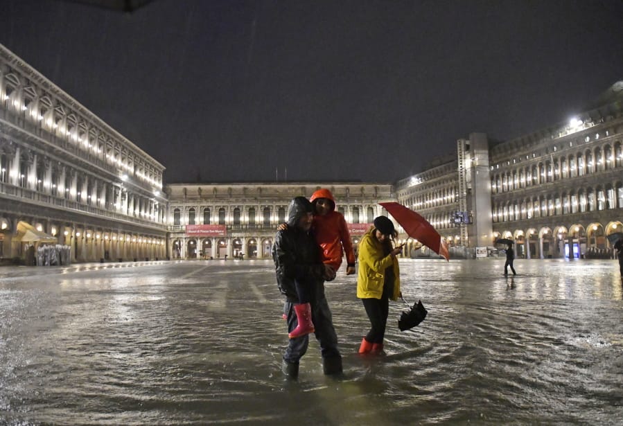 People walk in flooded St. Mark&#039;s Square on Thursday night in Venice, Italy.