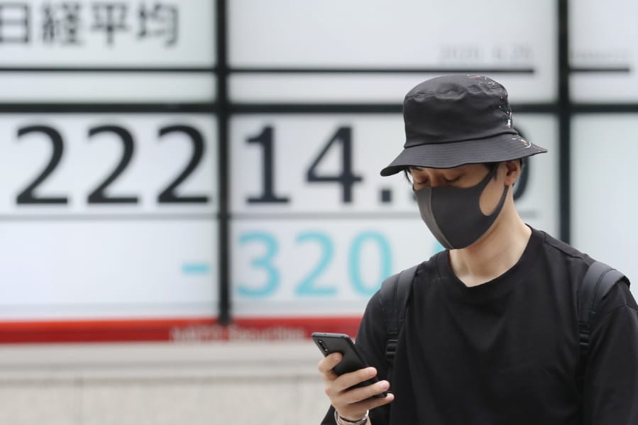 A man walks by an electronic stock board of a securities firm in Tokyo, Thursday, June 25, 2020. Shares declined in Asia on Thursday after a sharp retreat overnight on Wall Street as new coronavirus cases in the U.S. climbed to their highest level in two months, dimming investors&#039; hopes for a relatively quick economic turnaround.