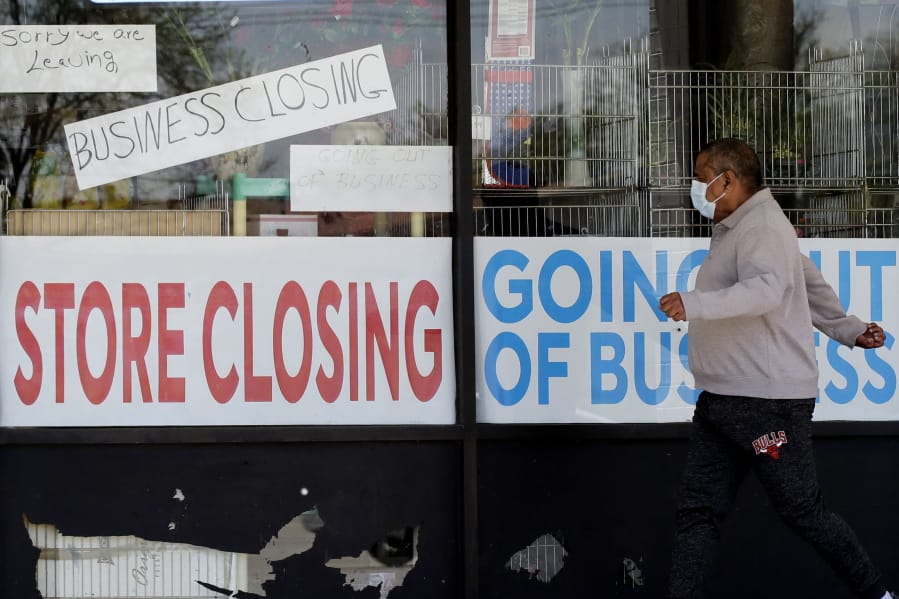 FILE - In this May 21, 2020 file photo, a man looks at signs of a closed store due to COVID-19 in Niles, Ill. U.S. layoffs surged in April revealing the deep economic hole that comes with shuttered offices, restaurants, stores and schools. (AP Photo/Nam Y.