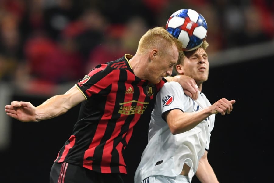 FILE - In this Oct. 19, 2019, file photo, Atlanta United defender Jeff Larentowicz, left, and New England Revolution midfielder Scott Caldwell battle for a header during round one of an MLS Cup playoff soccer game in Atlanta. Atlanta United veteran defender Jeff Larentowicz, who serves as an executive board member for the players union, said Thursday, June 4, 2020, he has safety concerns about an agreement announced Wednesday for a MLS tournament in Orlando in July.